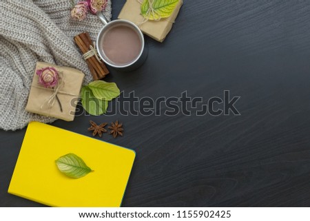 
Autumn composition. Hot chocolate, gifts, notepad, knitted blanket, autumn leaves, roses on a black background. Flat lay, top view, copy space