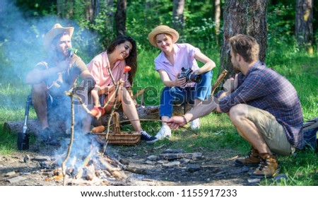 Hikers sharing impression of walk and eating. Weekend hike. Picnic with friends in forest near bonfire. Company having hike picnic nature background. Tourists with camera relaxing checking photos.