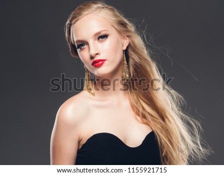 Beautiful blonde hair young happy woman with red lips curly hairstyle and earrings over gray background female model portrait