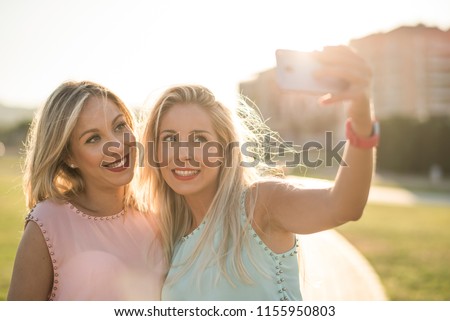Happy sisters taking selfie after shopping in sunset image