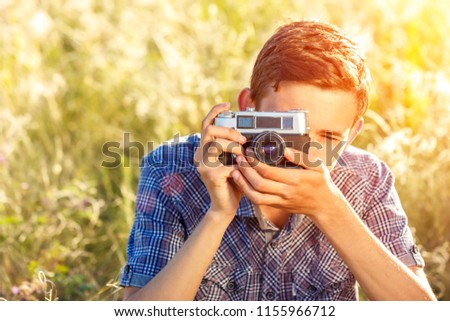 a young man with a camera taking pictures of the natural background sun rays tinted