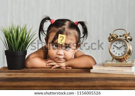 cute and confused lookian asian toddler with question mark on her forehead. concept of child learning education, growth and development. Royalty-Free Stock Photo #1156005526