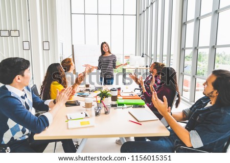Multiethnic diverse group of creative team or business coworker clapping hands in project presentation meeting leading by Asian woman. Success teamwork, modern office work, or startup company concept Royalty-Free Stock Photo #1156015351