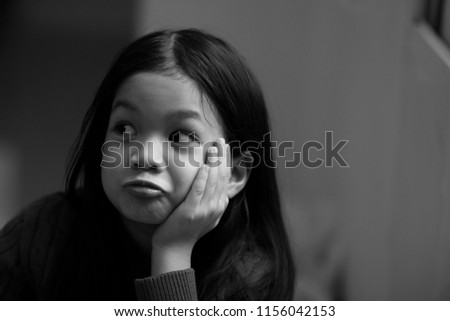 Image of 6 years old Asian girl rest her chin with her hand and making funny face.Wind.Girl look happy and natural.Concept of Asian  home sweet home.Preteen lifestyle.