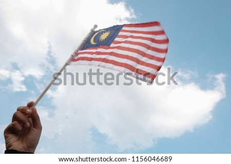 Malaysia flag or Jalur Gemilang has been held and isolated with blue sky background. Independence day or Merdeka celebration. 