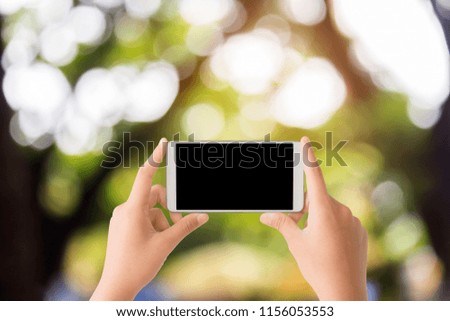 woman use mobile phone and blurred image of the tree in the garden with beautiful bokeh from the sun light