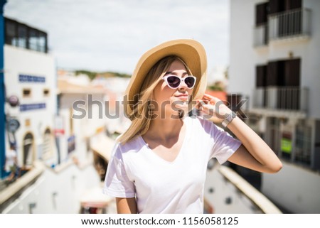 Outdoor fashion portrait girl wearing hat, trendy sunglasses sitting on handrail, amazing view of city from the top