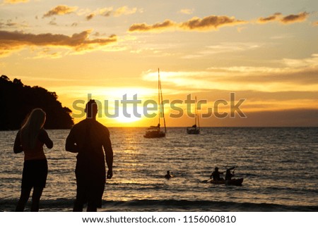 a couple stand watch sunset take photo by the beach