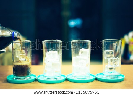 Glass of soda waters or is a sweetened and carbonated drink, which including of caffeine. Side view of refreshing soda with bubbles and ice on top.