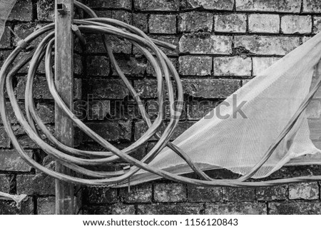Black and white photo with a broken brick wall, wound wire and cloth
