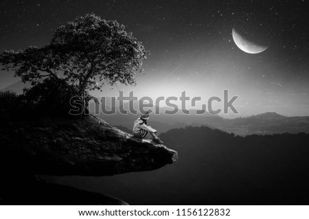 The black and white girl sat on the cliff, watching the moon half-moon in the beautiful night.