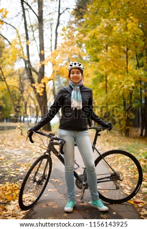 Photo of woman in helmet, jeans next to bicycle