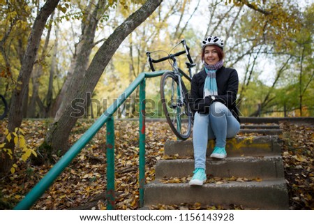 Photo of brunette sitting on stairs next to bicycle