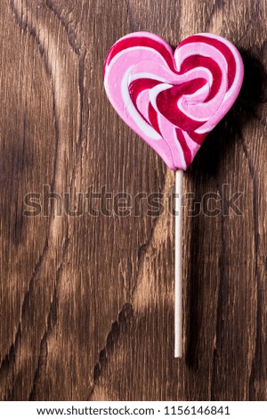 Heart shaped lollipop for Valentine's Day on the old wooden background. Vintage toned picture.