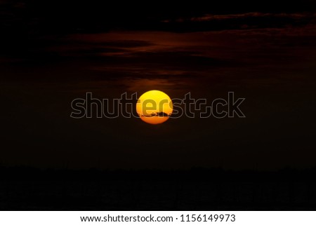 Big sunset at the dark background with clouds and black space.