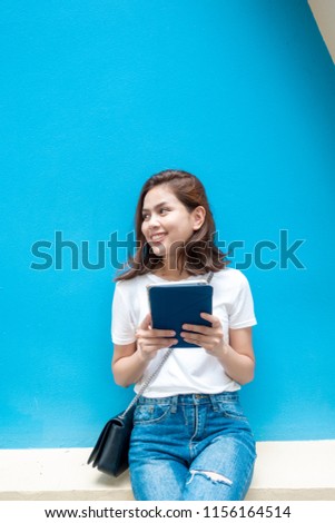 portrait of beautiful university student is smiling on blue wall background 