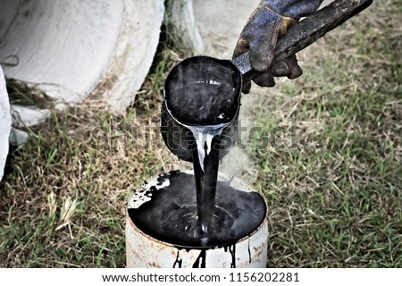 a man working with hot tar Royalty-Free Stock Photo #1156202281