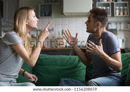 Angry millennial couple arguing shouting blaming each other of problem, frustrated husband and annoyed wife quarreling about bad marriage relationships, unhappy young family fighting at home concept Royalty-Free Stock Photo #1156208659
