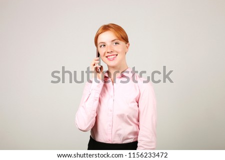 Portrait of young beautiful businesswoman with red hair talking on mobile cell phone, positive emotions. Smiling attractive female having smartphone conversation. Isolated white background, copy space