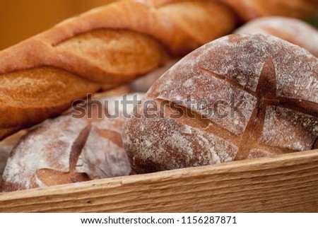 several rye bread buns and a wheat baguette lie in a wooden box