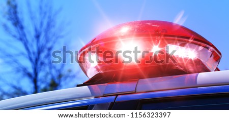 Police car with focus on red siren light. Colorful red siren on the roof of a police car in a real intervention. Beautiful red siren lights activated in full policemen operation. Red light flasher.
