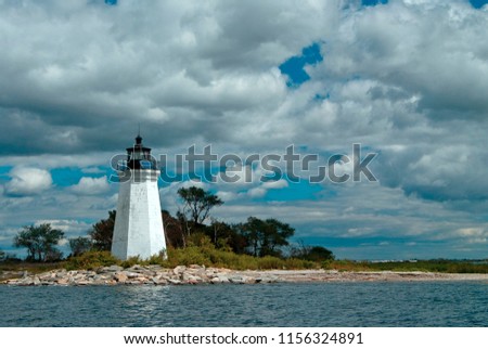 Black Rock Harbor lighthouse, also referred to as Fayerweather Island lighthouse, is illuminated by the sun though the clouds. Royalty-Free Stock Photo #1156324891
