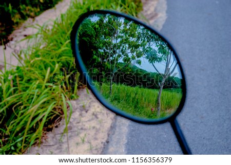 a mirror on a motorcycle with natural landscape reflecting on it