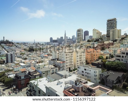 Top view typical Victorian residential houses in San Francisco and downtown skylines in background. Aerial famous Russian Hill neighborhood cityscape with Bay Bridge and Treasure Island in distance