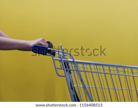 Shopping Lifestyle Concept. Part of Customer with Empty Cart against yellow Wall, ready for Pickup or Buying Products