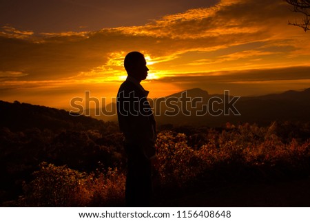 Silhouette of the man standing on the mountain in the morning.