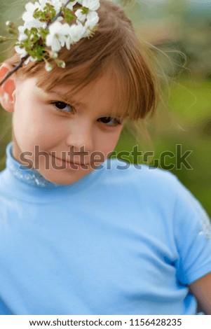a little girl dressed in a blue dress and a branch of apple blossom