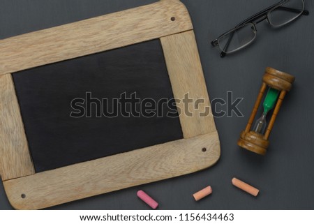 Table top view aerial image of back to school of education season background concept.Flat lay black board with chalk and hourglass on modern rustic wooden plank.Free space for creative design text.