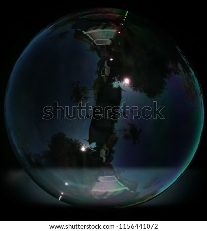 A digitally manipulated photograph of a luminous soap bubble that has landed softly on a hard surface.