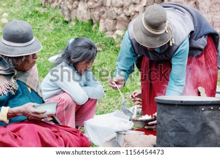 Three generations of native american women eating in the countryside. Aymara culture.