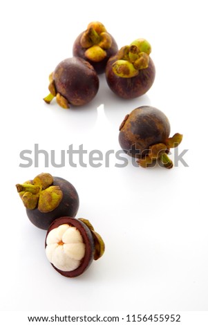 tropical fruits whole mangosteen and another cut in half on white background