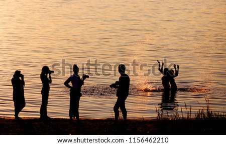Silhouette of the photographers at sunset.  Photographers taking photos. Silhouettes of people with cameras, photo seminar, photo school, photography courses, silhouettes of people on river background