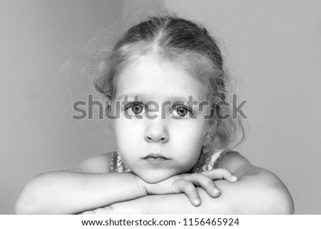 Little blonde hair girl with sad eyes looking at the camera. Black and white picture.
