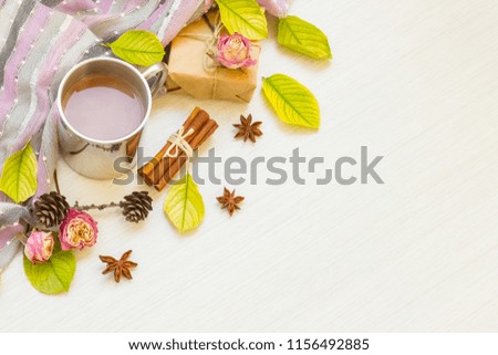 
Autumn composition. Hot chocolate, autumn leaves, badon, cinnamon, cones, roses, gifts, scarf on a light wood background. Flat lay, top view, copy space