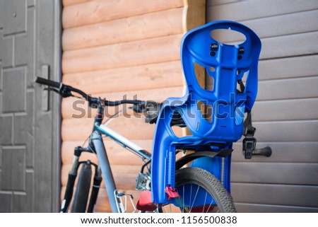 Bike with children carrying seat attached. Cycle with kids transportation equipment stand near wooden garage. Family safety sport activity concept.