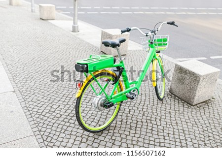 modern electric green bicycle parked at the sidewalk in the city
