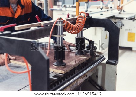Furniture production concept: man working at machine and making furniture part