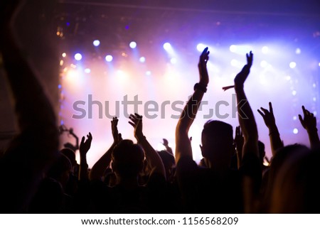 Crowd at concert. Stage lights and hands in the air. People enjoying the party.