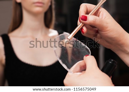 makeup artist mixing foundation and oil on a glassy surface before applying it on a face of a model. concept of natural make up Royalty-Free Stock Photo #1156575049