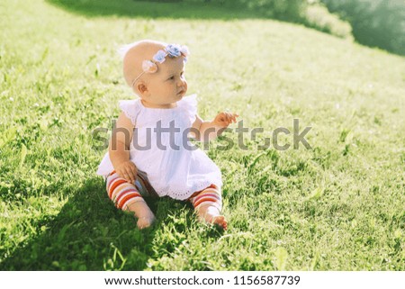 Baby at summer outside. Adorable little girl on green nature background. Image of childhood. Parents and activity with kid outdoors. Beautiful happy child have fun on grass of meadow.