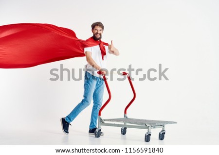 A man in a red raincoat holds an iron trolley by the handles                       