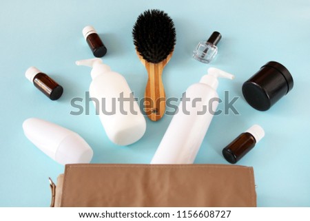 Jars and containers with cosmetics and cotton buds with disks from a yellow cosmetic bag on a blue background. Top view, flat lay, cosmetic products, beauty shopping concept with free space for text, 