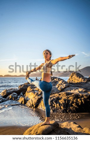 Woman training yoga on the beach at sunset