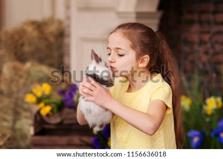little cute girl is kissing bunny rabbit at easter