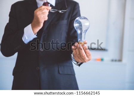 Senior business man holding light bulb. White male in suit looking happy. Half body shot. Business idea concept.