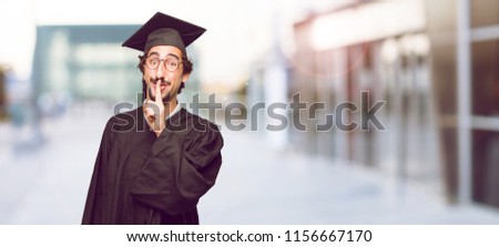 young graduated man leaning forward and whispering a secret with a serious and surprised look on face
